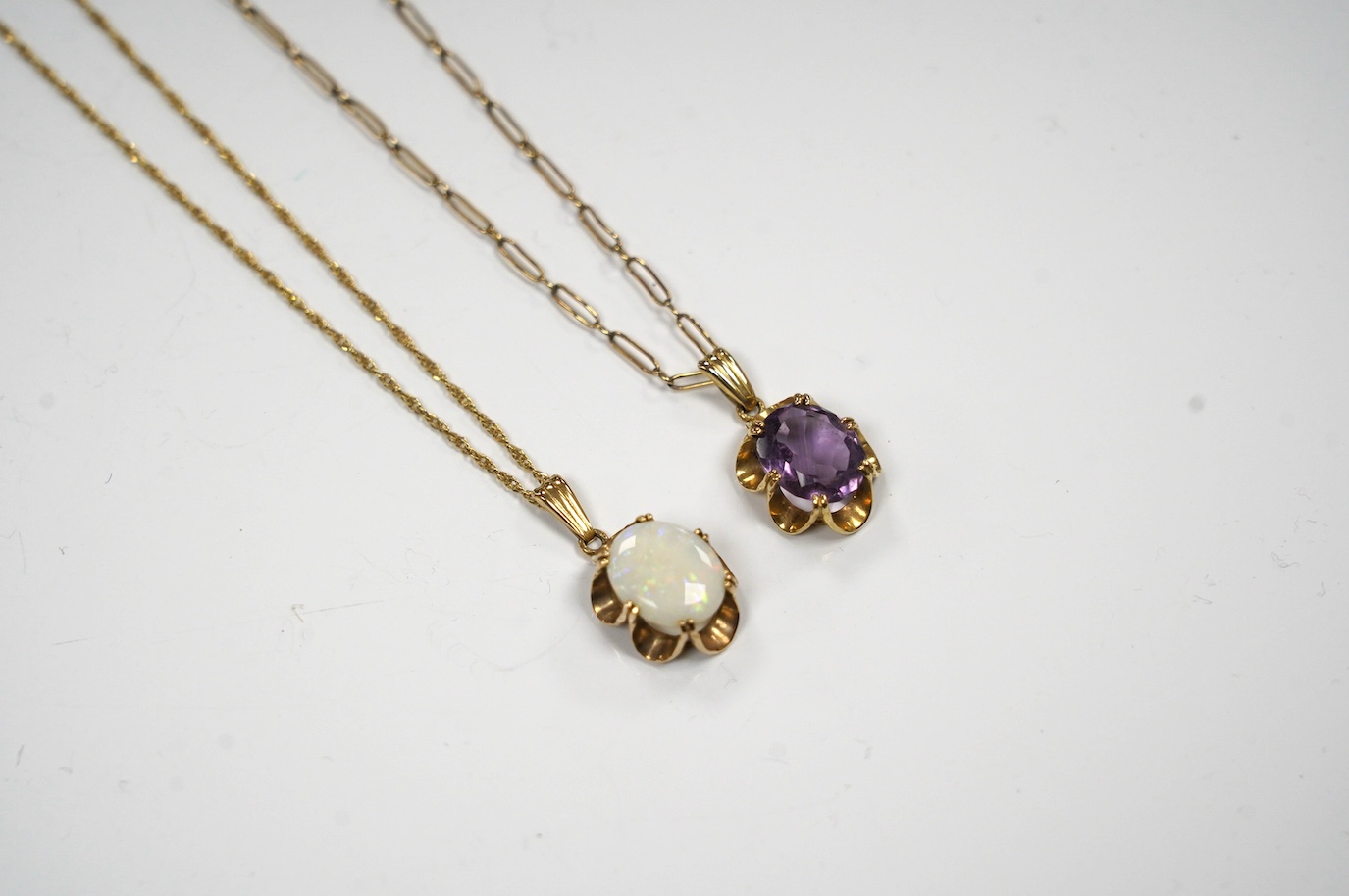 A modern 9ct gold and white opal set pendant, 21mm on a 14k chain, 46cm, gross weight 3.8 grams and a 9ct gold and amethyst set pendant on a yellow metal chain, gross weight 5 grams. Condition - fair